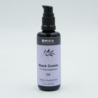 Bottle of Omica Organics Black Cumin Oil on a light gray background