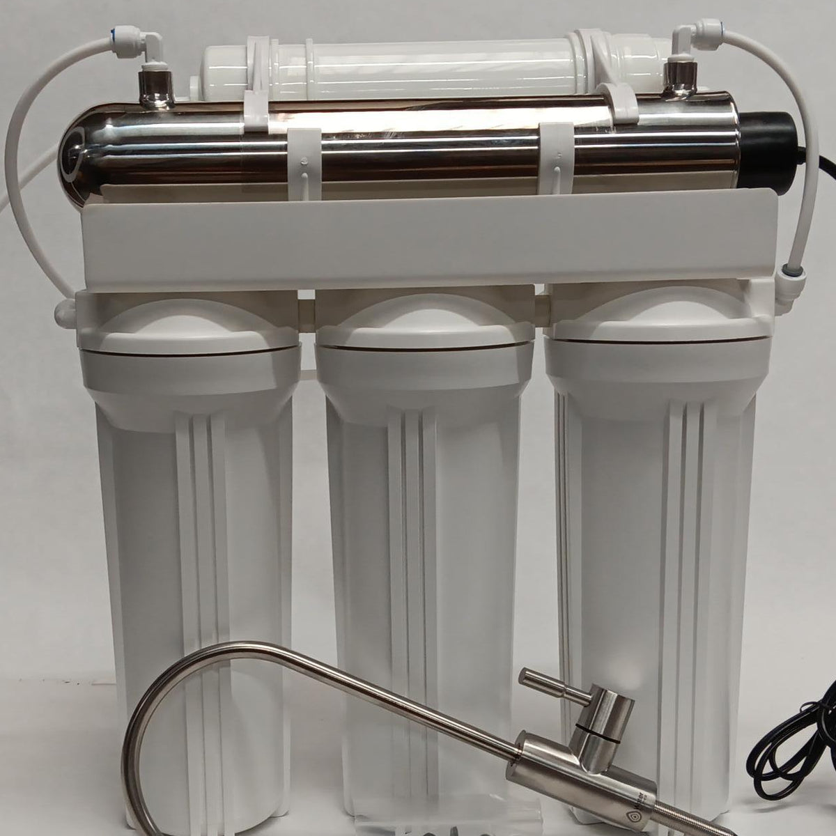 Water filtration system with three cylindrical tanks and a faucet on a white background