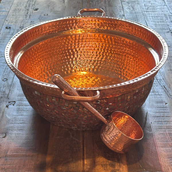 Omica Artisanal Mosaic Copper pot and ladle on a wooden surface.
